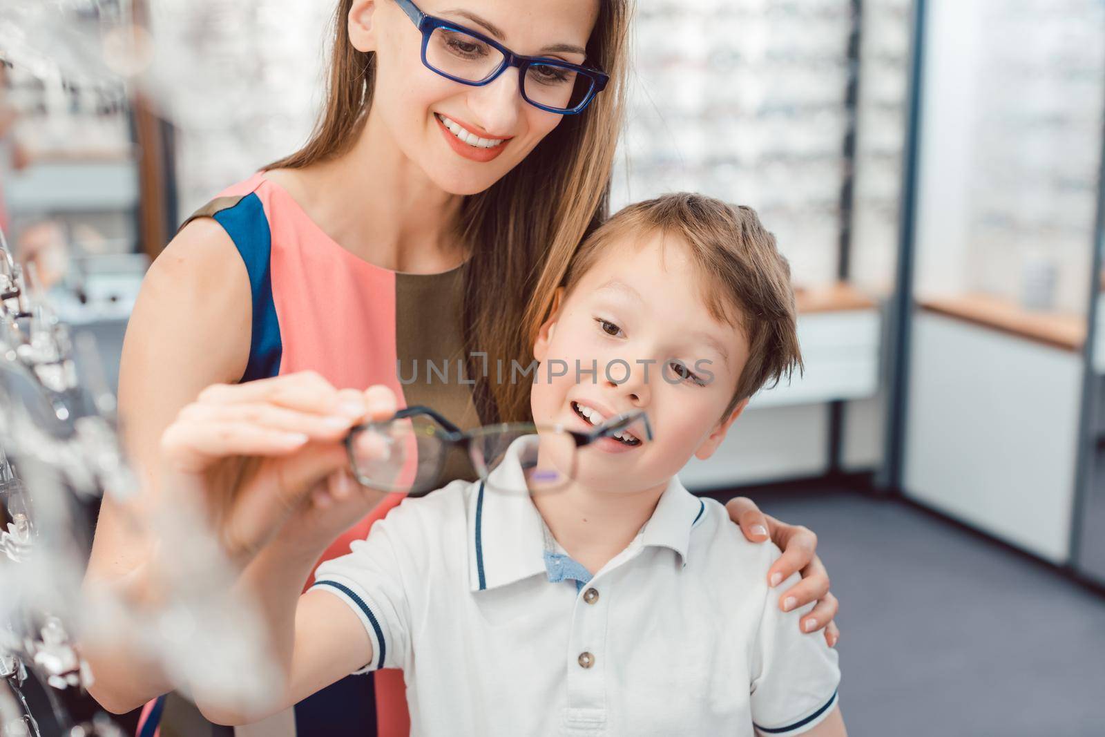 Mother and son both liking the eyeglasses offered in optician shop by Kzenon