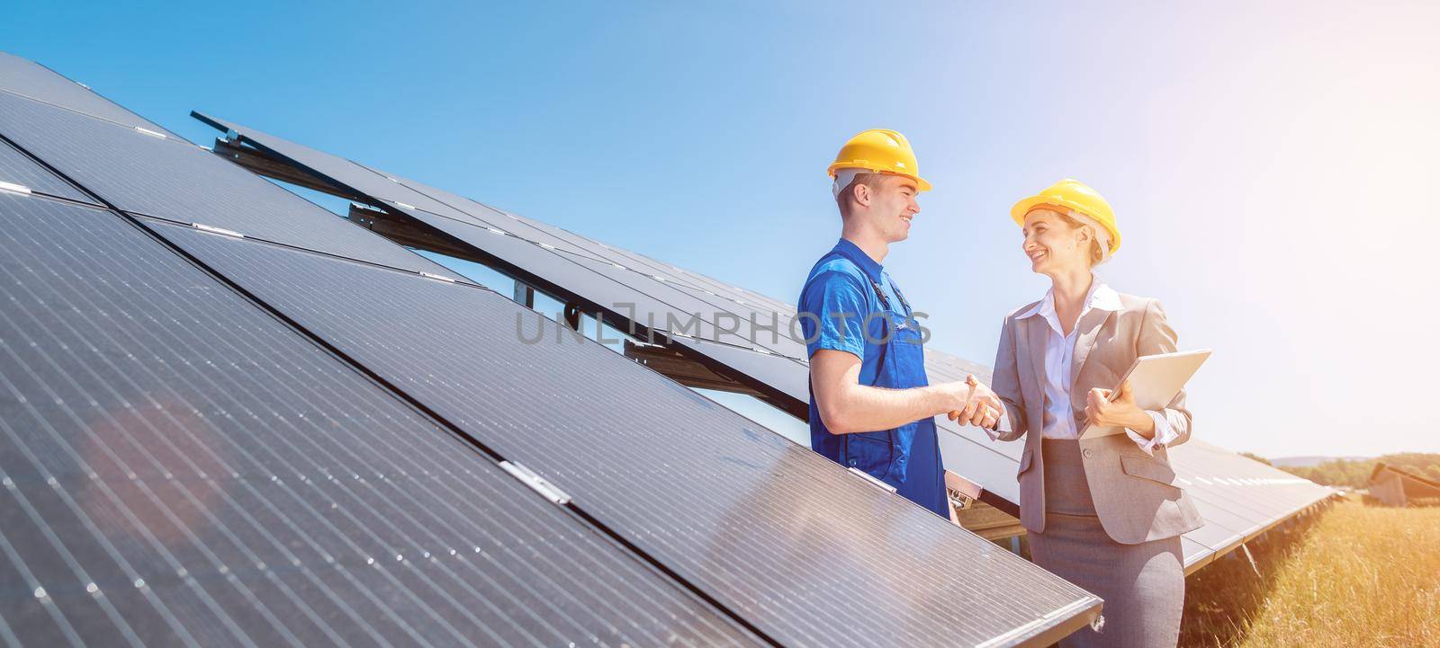 Construction worker and investor in solar power plant shaking hands by Kzenon