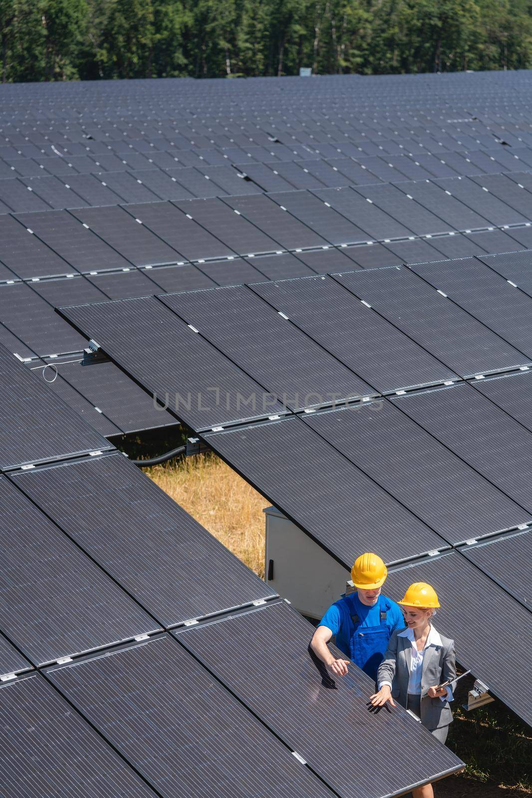 Two people standing amid solar cells in a power plant inspecting the modules