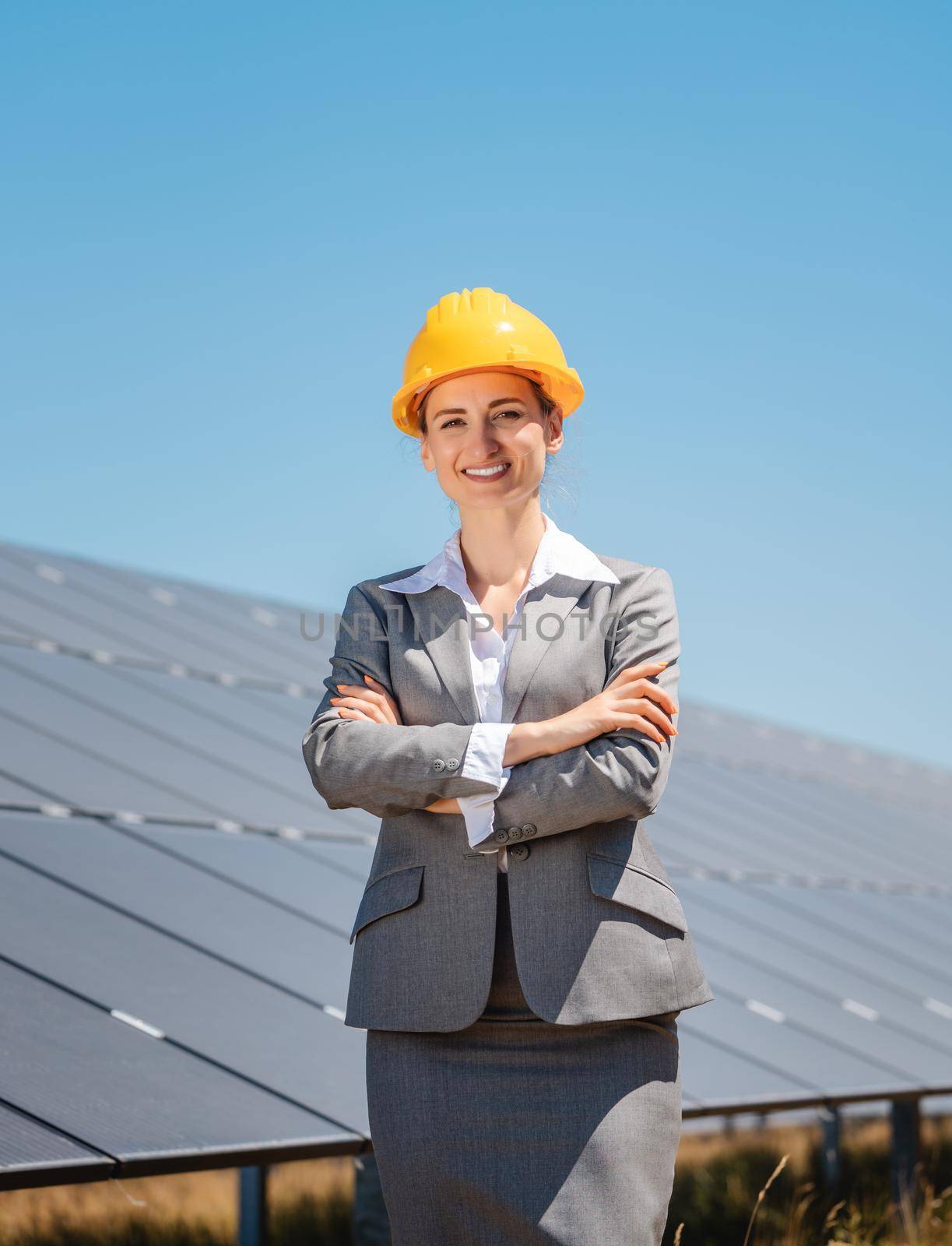 Woman investor in clean energy standing proudly in front of solar panels