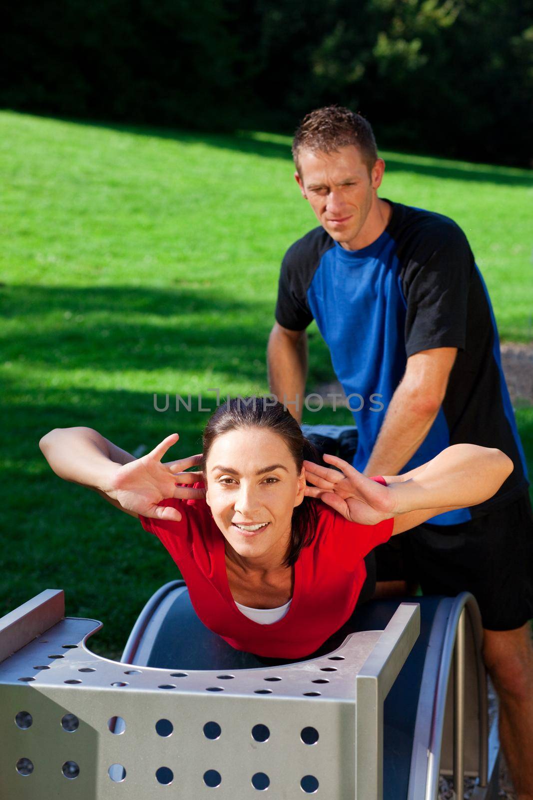 Mature woman does exercises with her personal trainer, having a lot of fun on a sunny day