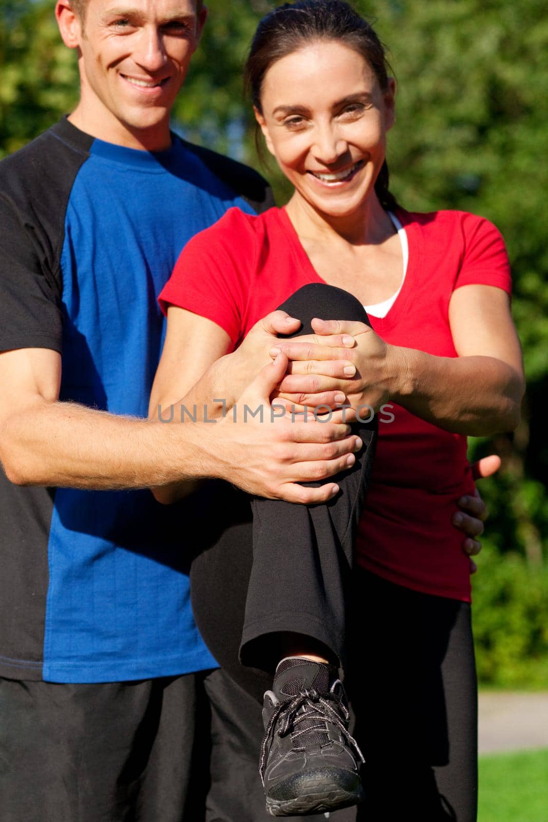 Woman does outdoor stretching with her personal trainer on a great summer day