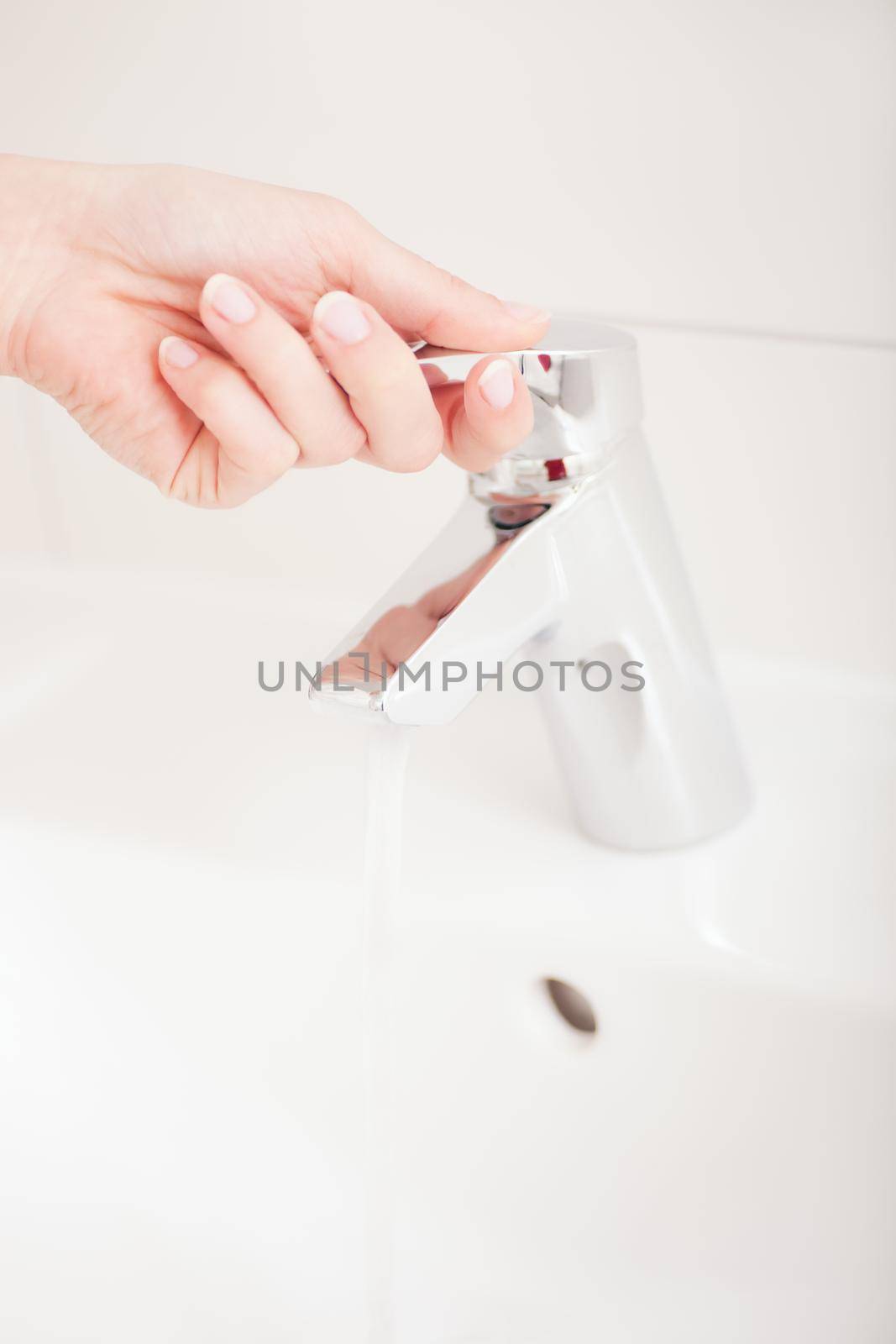 Woman (just hand to be seen) opening the water tap to wash her hands