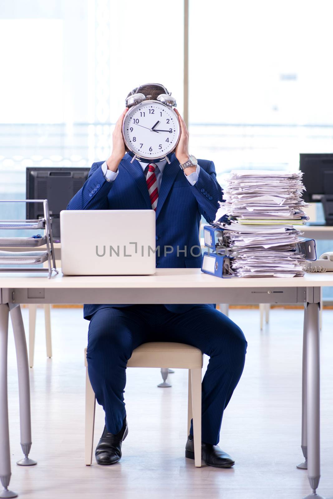 Businessman employee in urgency and deadline concept with alarm clock