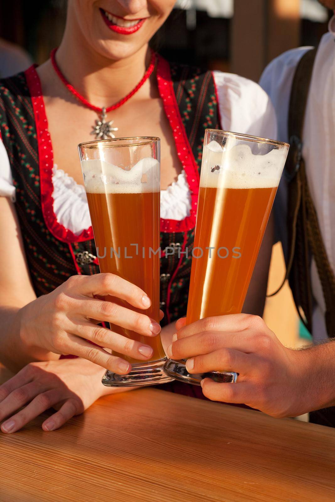 Couple in Bavarian Tracht clinking glasses by Kzenon