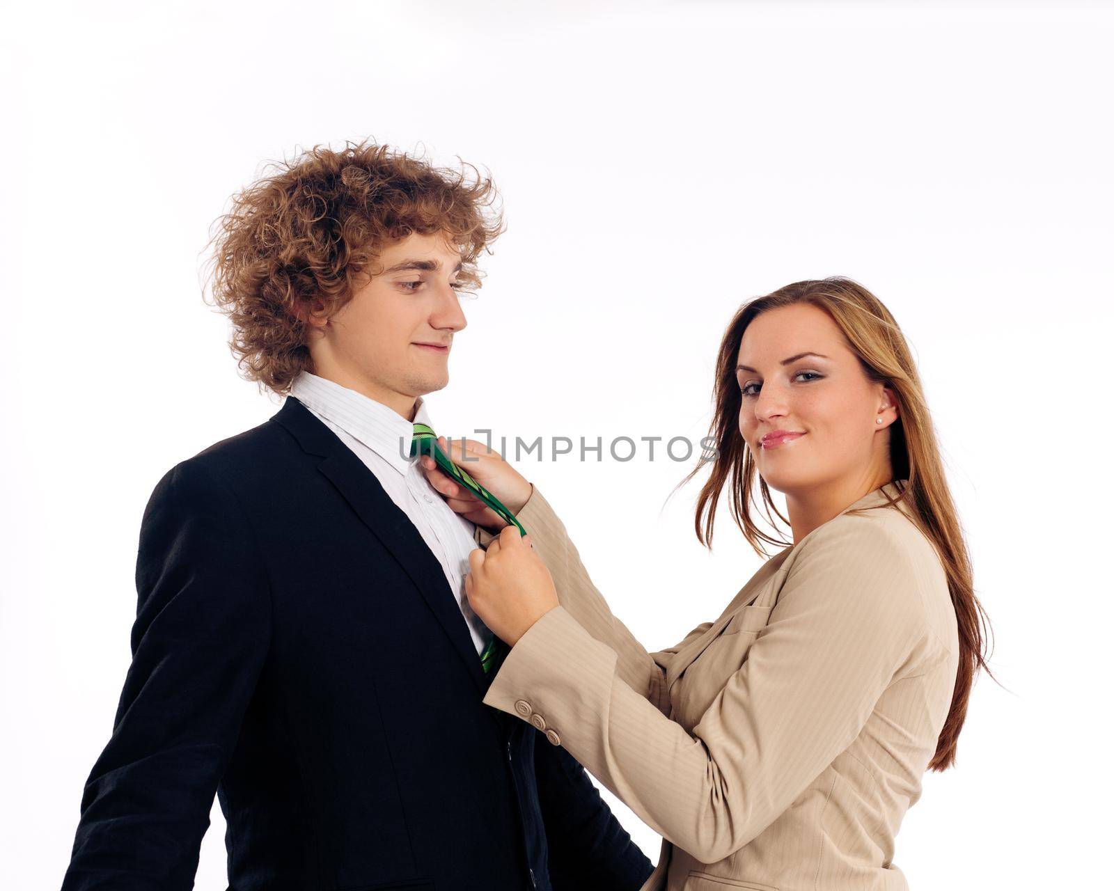 Business people standing in a studio, she is binding his tie