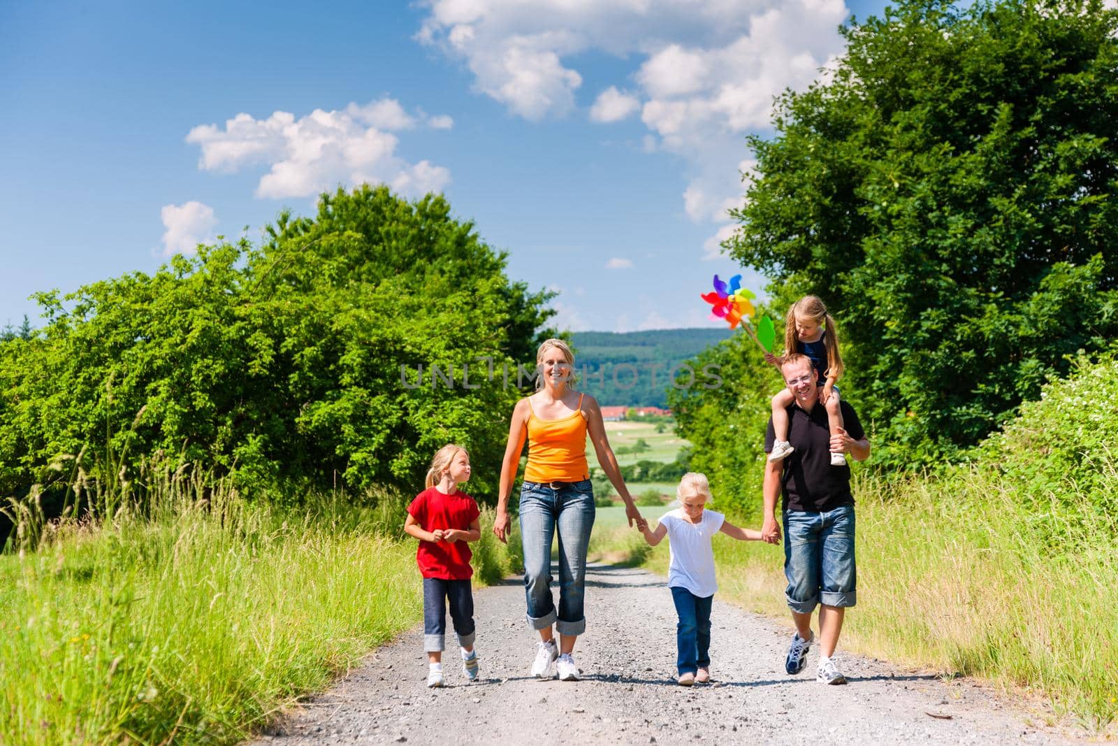Family walking down a rural path on bright summer day