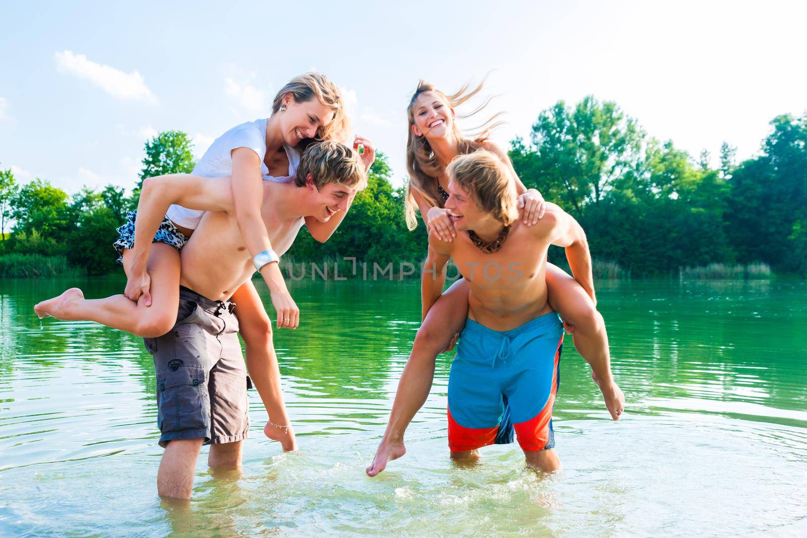 People having fun at lake in summer by Kzenon