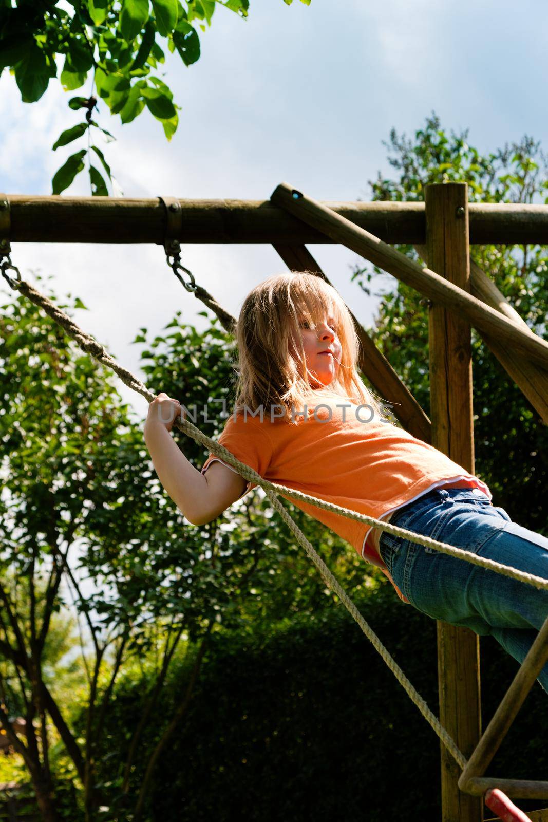 Little girl on a swing in a garden on a beautiful summer day