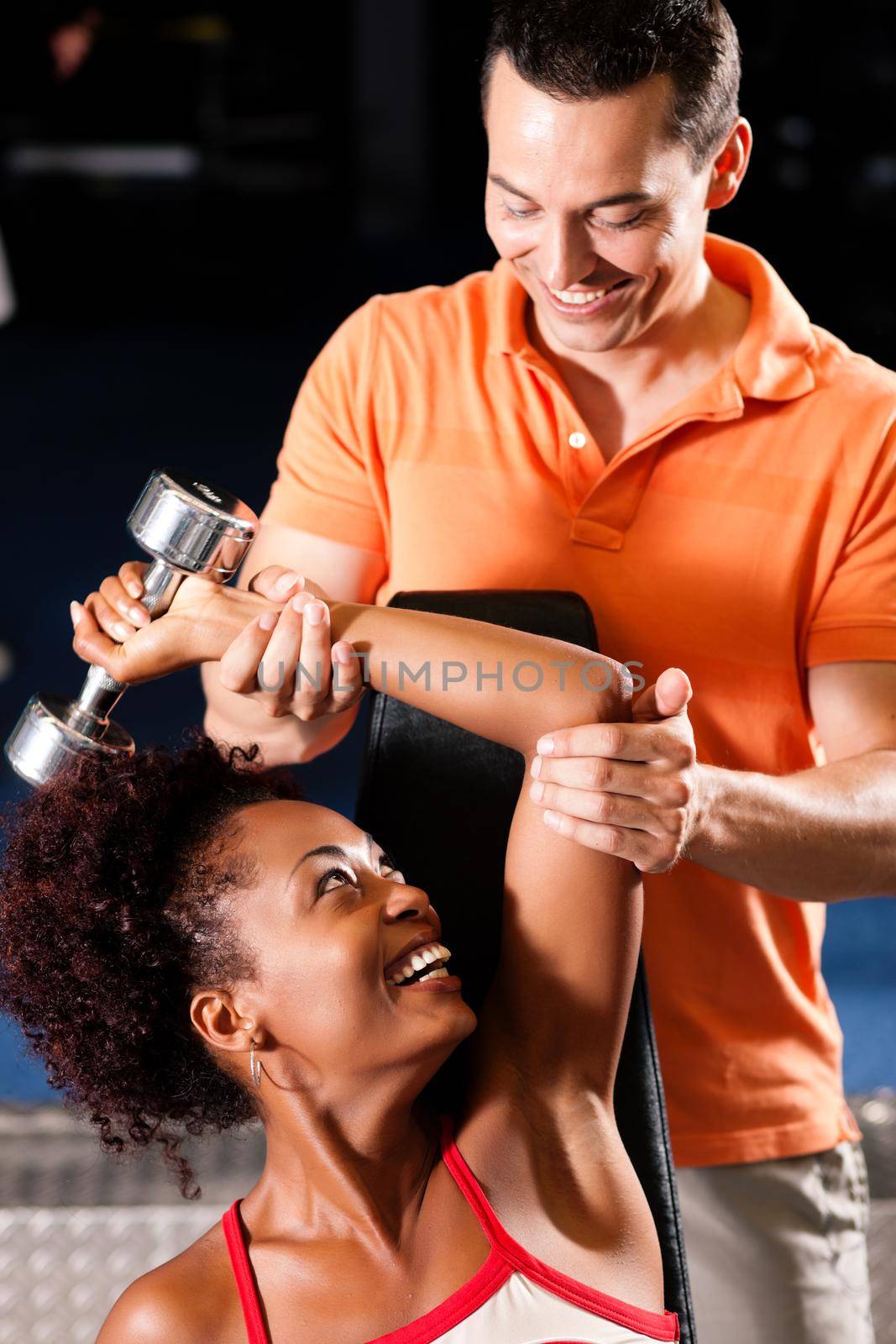 Woman with her personal fitness trainer in the gym exercising with dumbbells