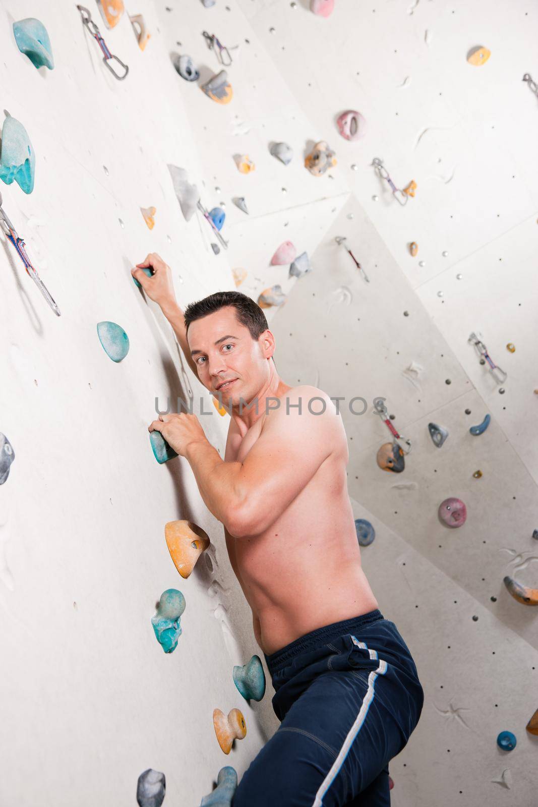 Man exercising at a climbing wall in a gym