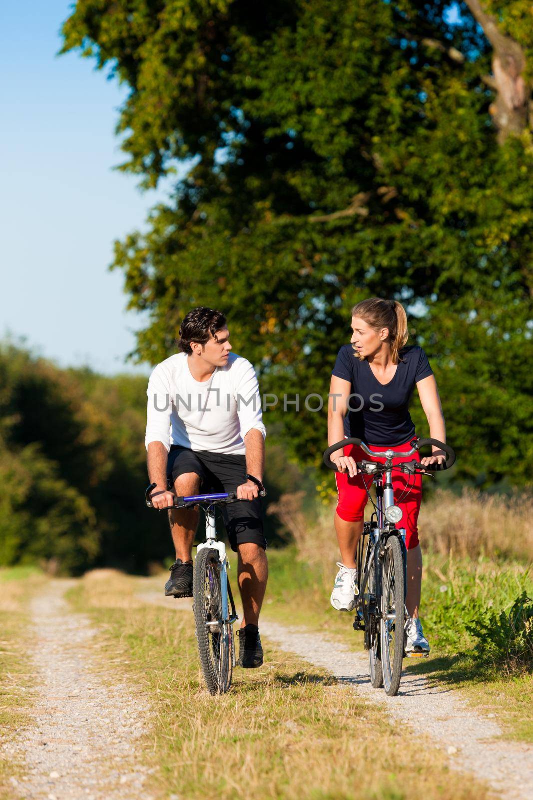 Sportive Man and woman exercising with bicycles outdoors, they are a couple