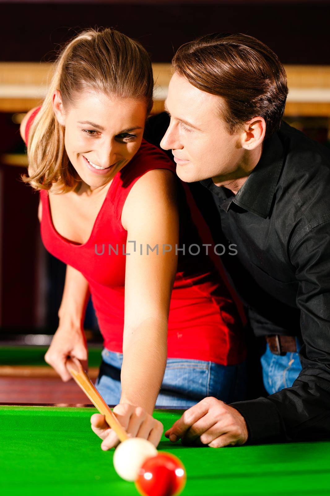 Couple (man and woman) in a billiard hall playing snooker