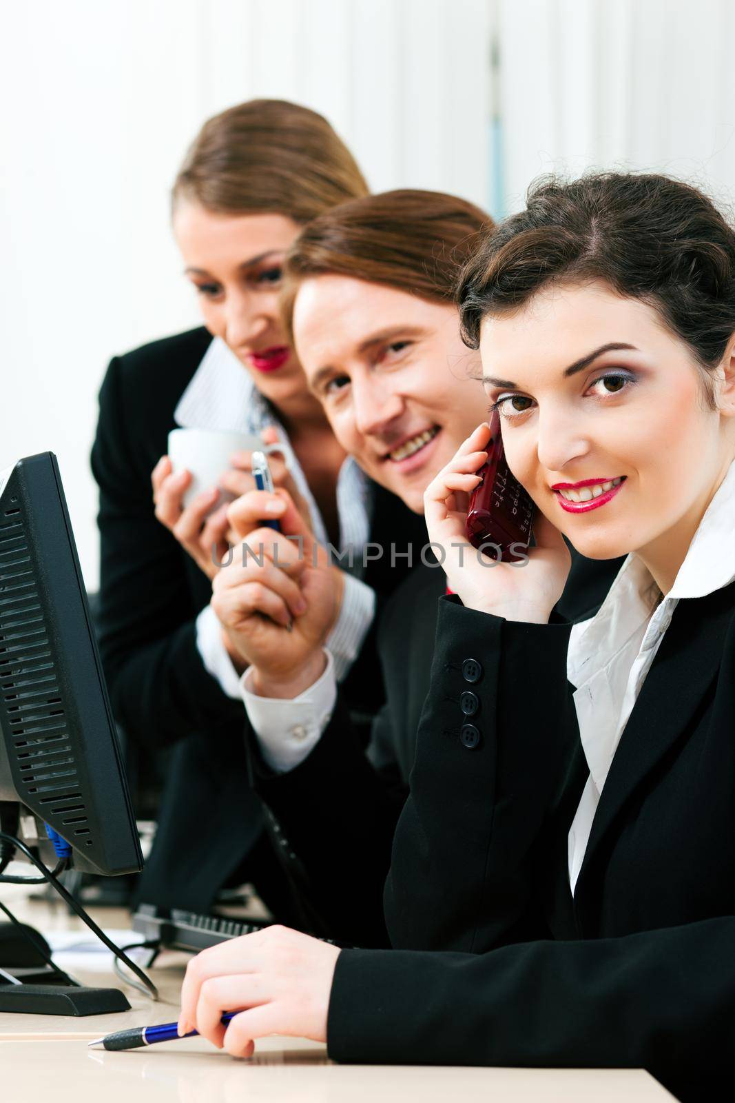 Small business team working in the office on their phones and computers in a shared project