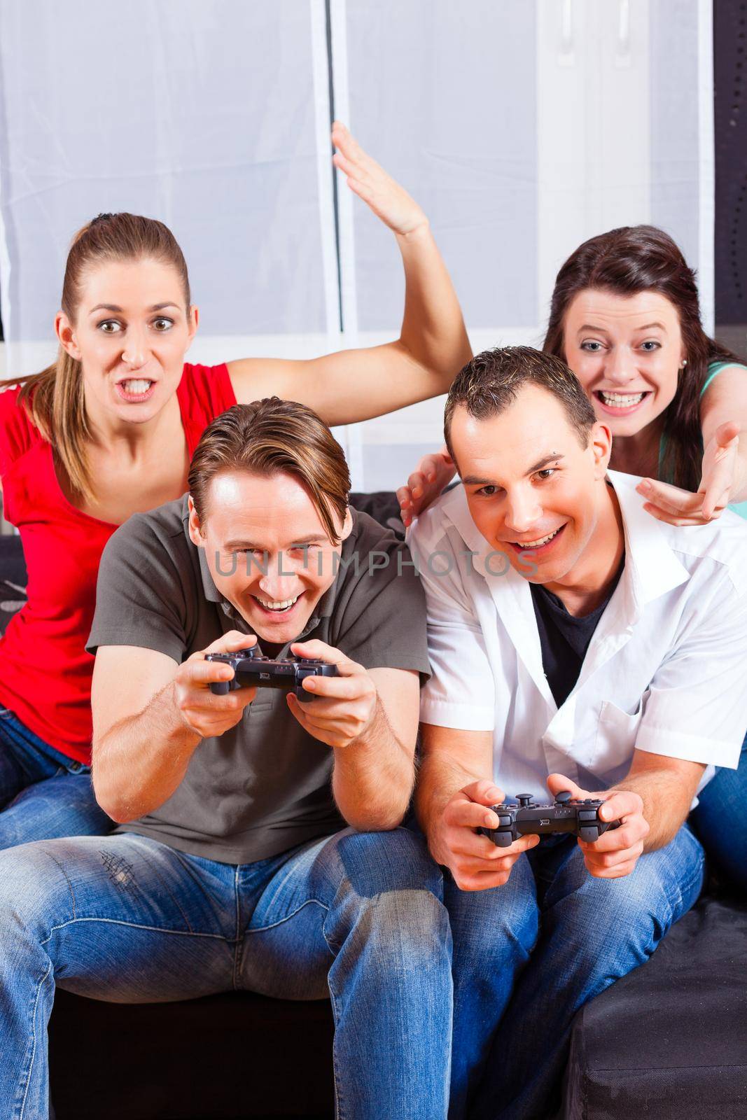 Friends - two couples - sitting in front of game console box and do have lots of fun