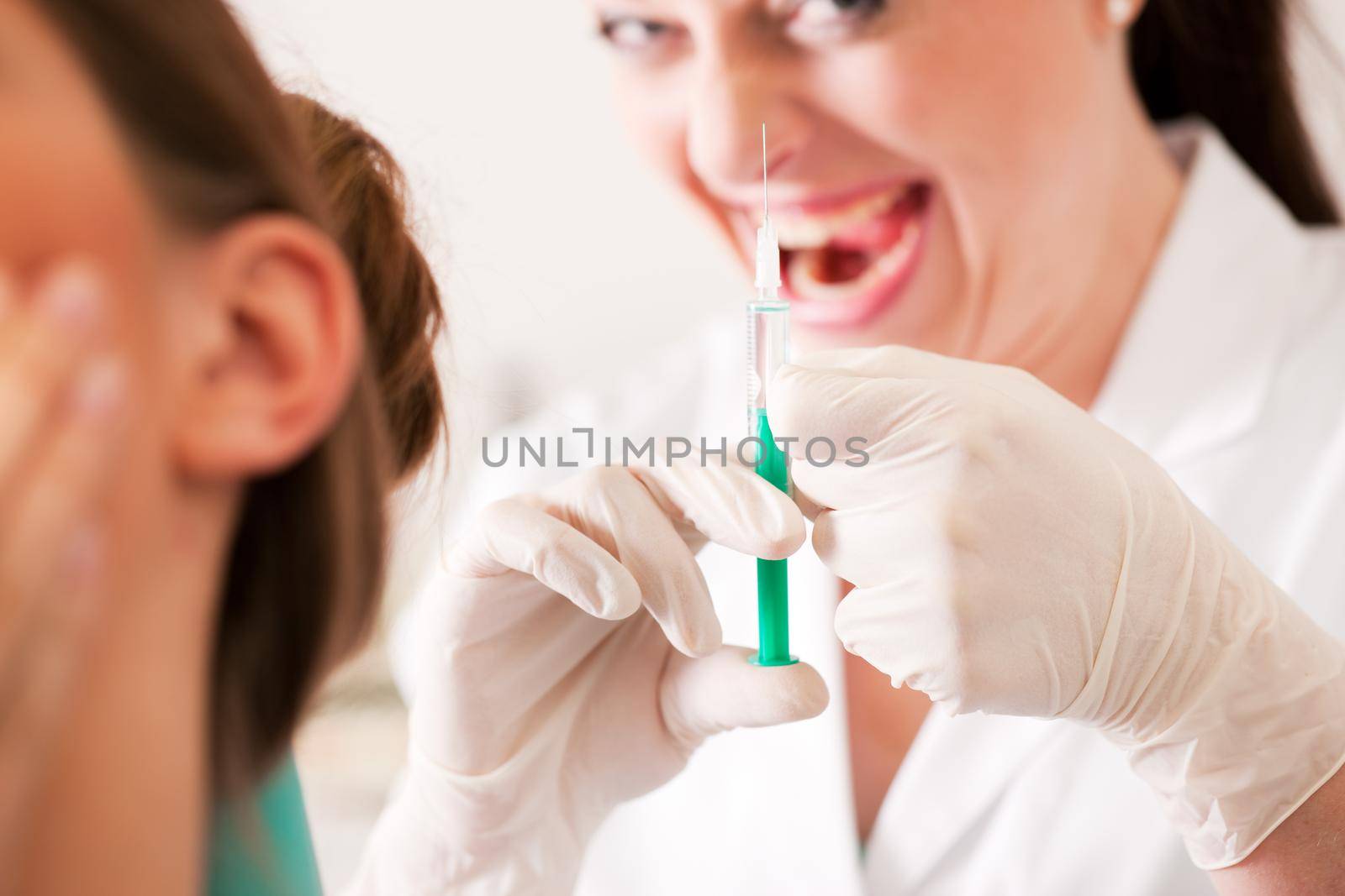 At the dentist - a female patient is getting ready to receive a anesthetization syringe, the nurse has a very disturbing diabolic smile (focus on hand of nurse)