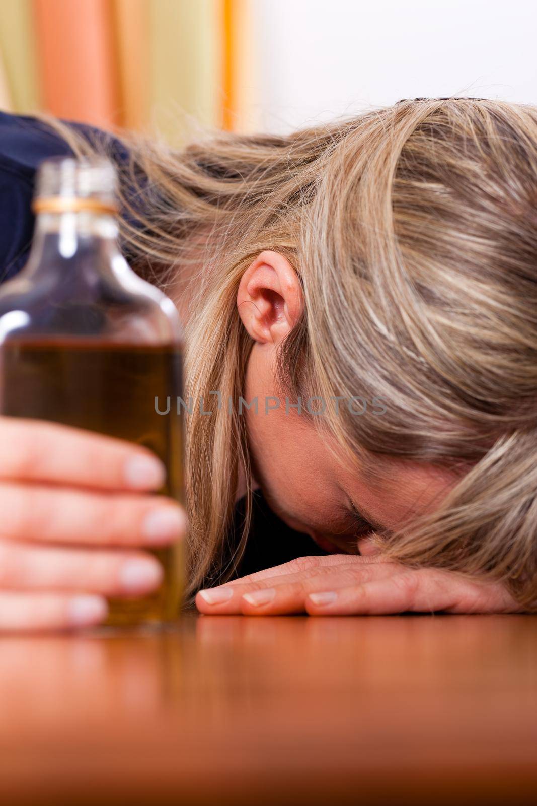 Woman sitting at home drinking way too much brandy, she is addicted