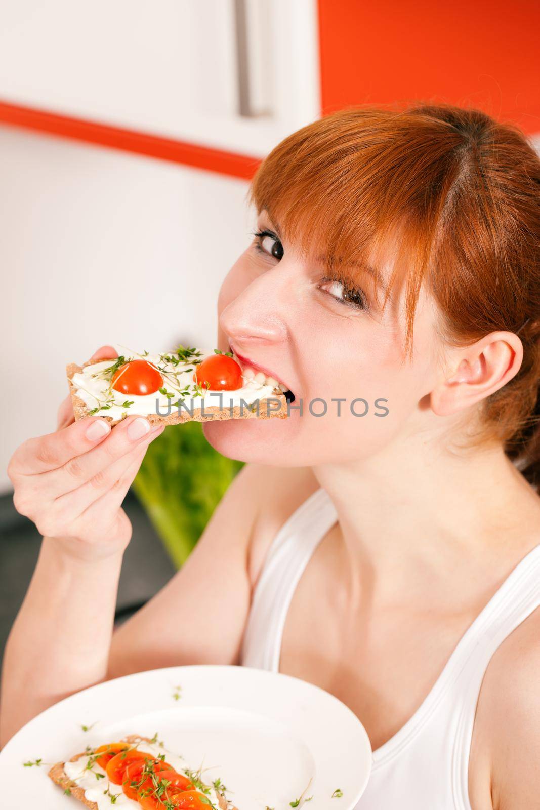 Woman eating healthy in her diet, having a crispbread with cream cheese, cress, and tomatoes