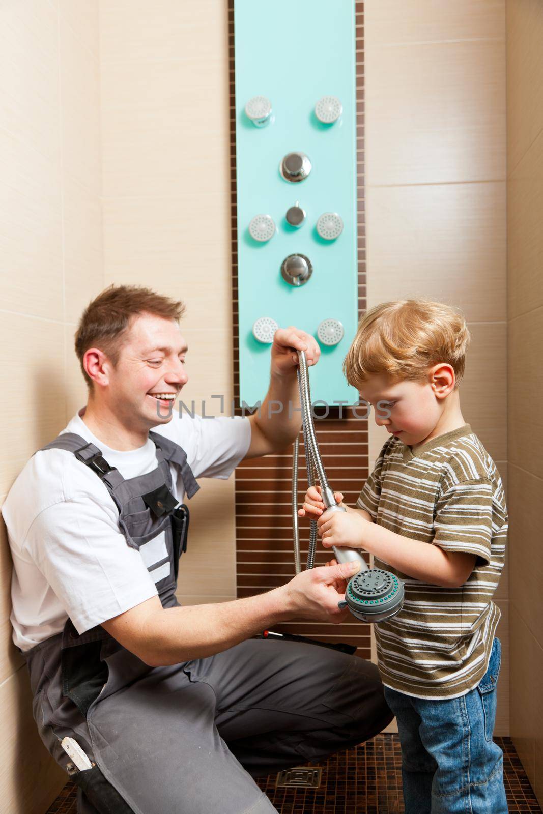 Father, who is a Plumber, installing a mixer tap in a bathroom; explaining what he does to his son