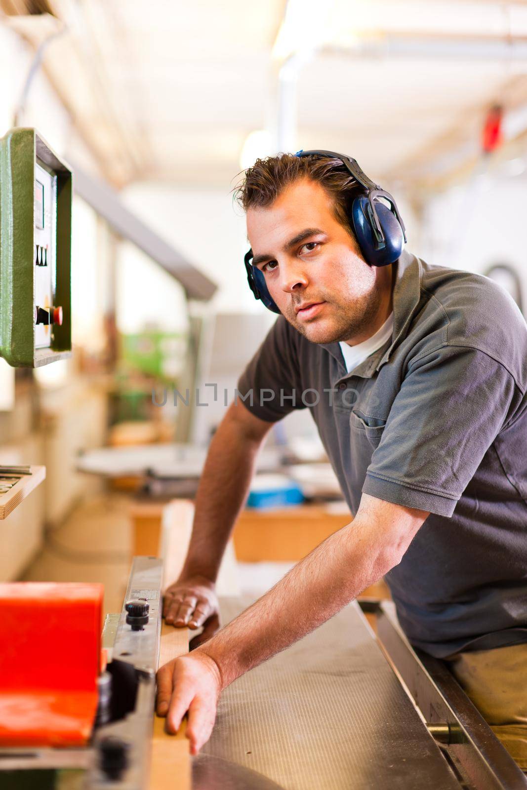 Carpenter is standing on electric cutter with ear protection