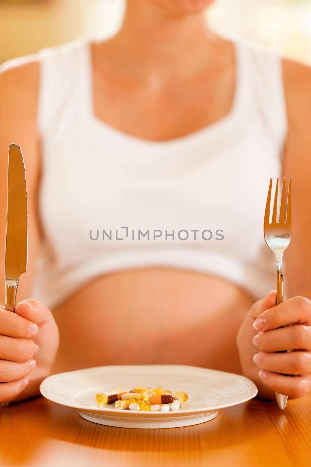 pregnant woman with a plate full of pills and capsules in front of her