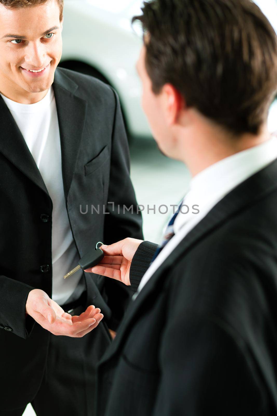 Man at a car dealership buying an auto, the sales rep giving him the key