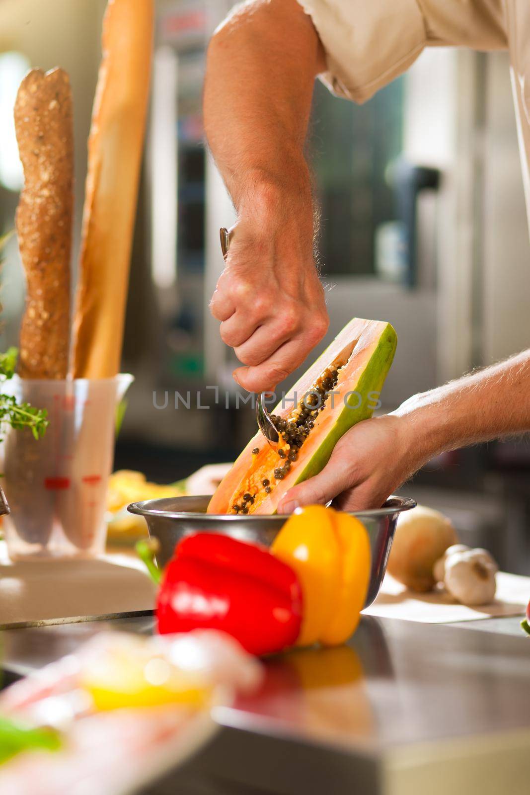 Chef preparing fruits in restaurant or hotel kitchen by Kzenon