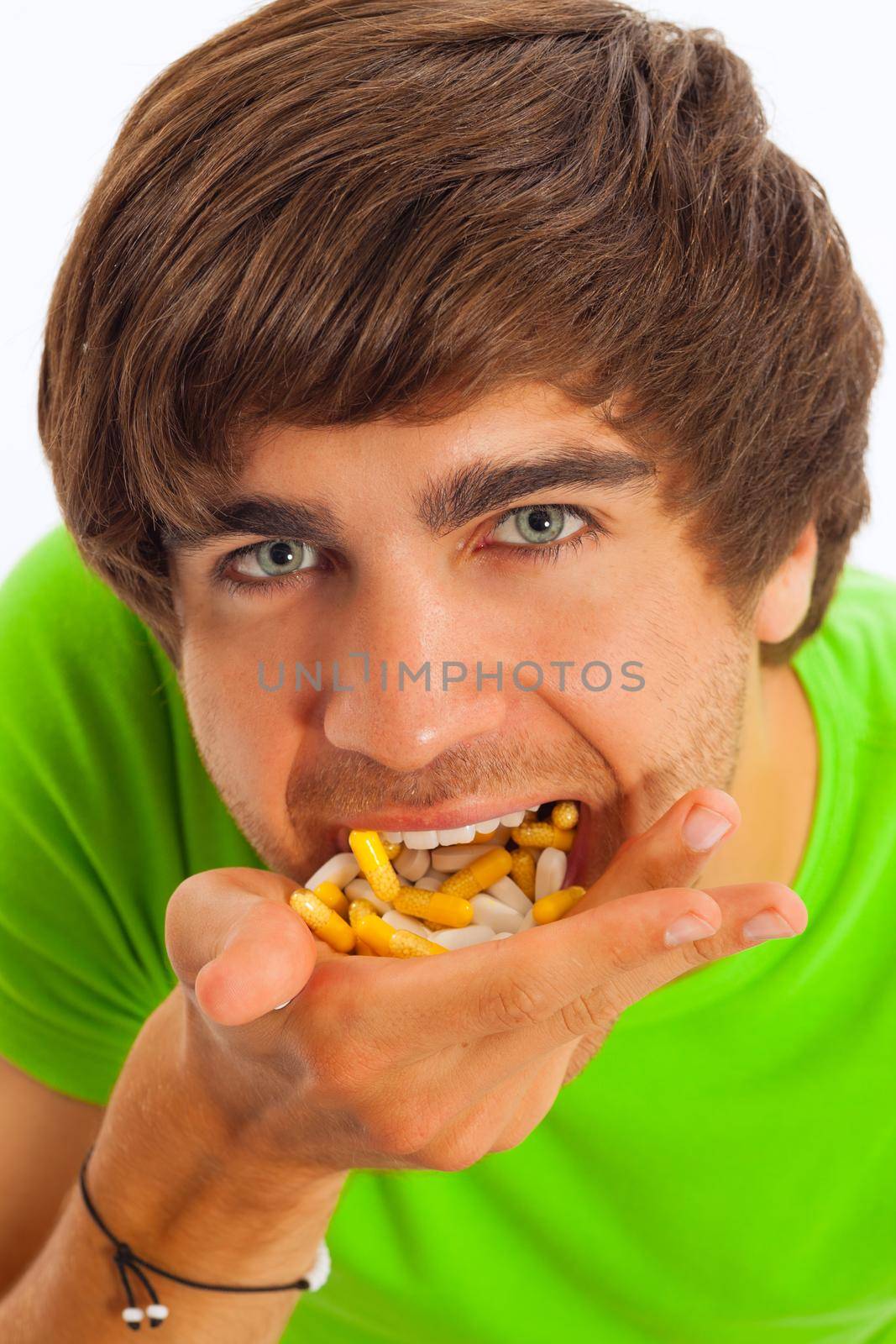 Young man is feeding himself pills and drugs, close-up