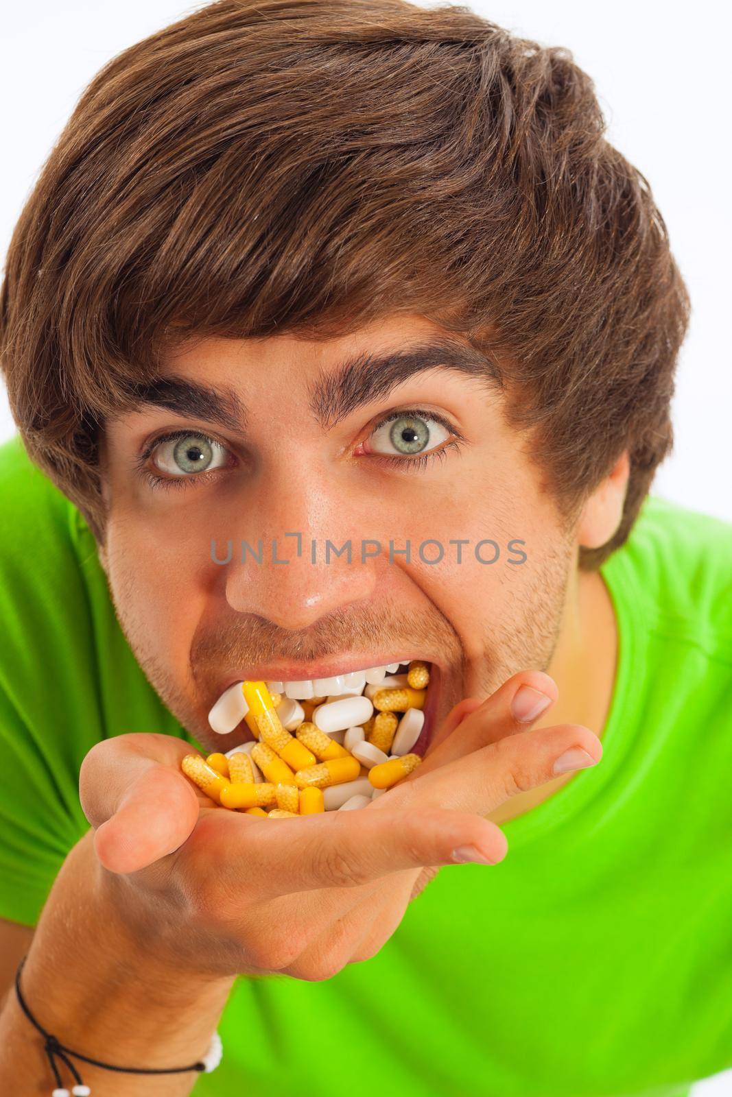 Young man is feeding himself pills and drugs, close-up