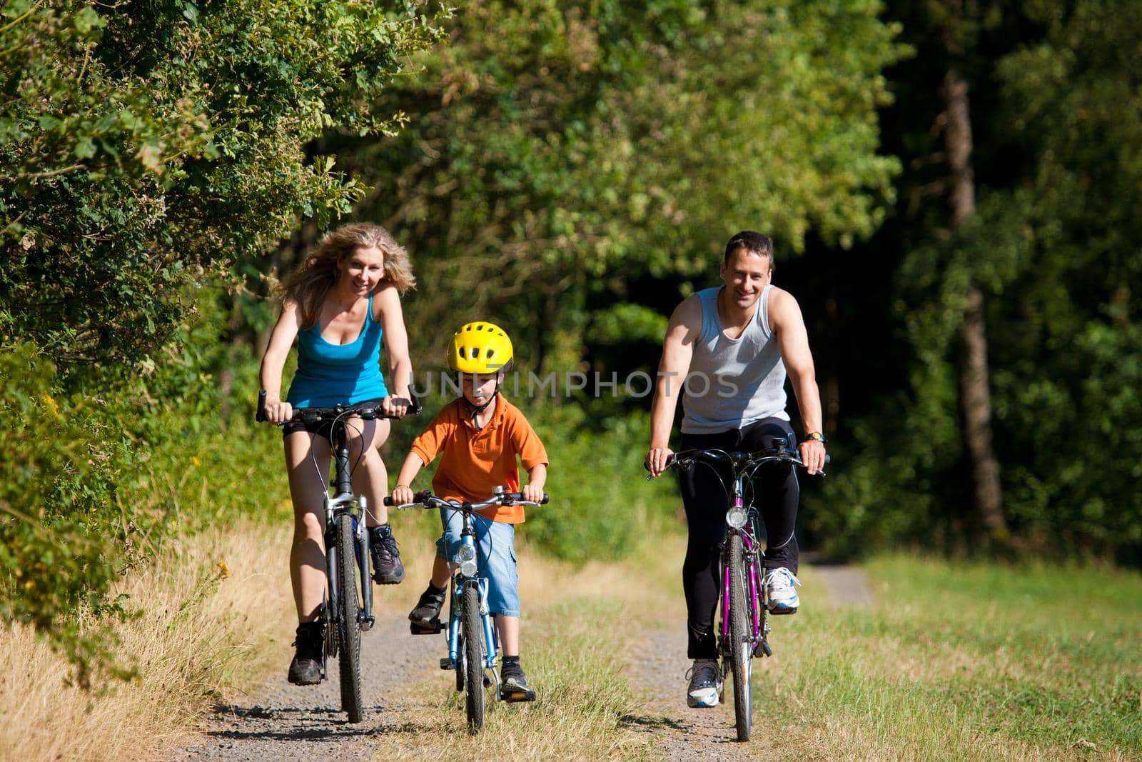 Family with child on their bikes on a summer day in sport outfit, FOCUS ON SON ONLY