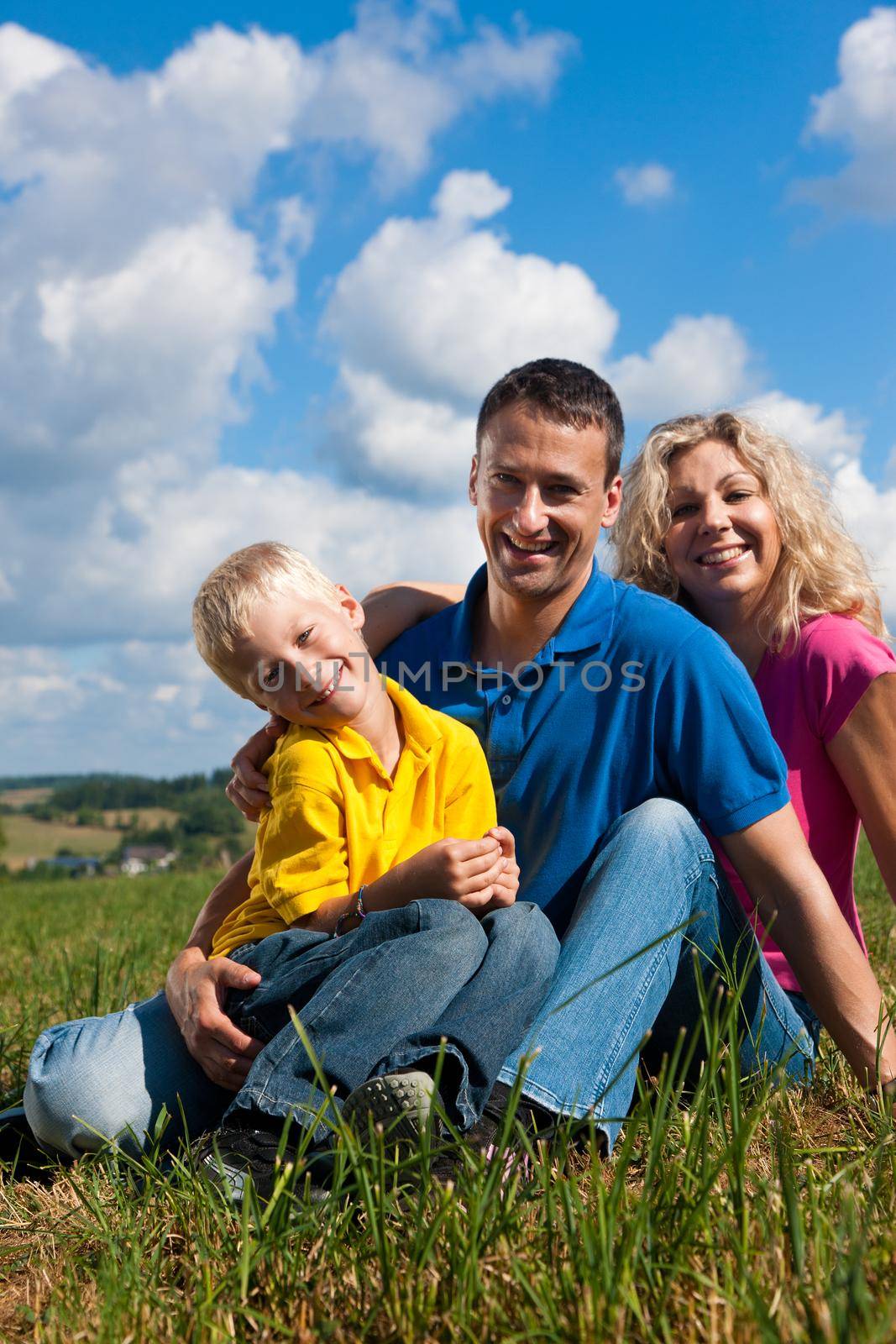 Family sitting on meadow  by Kzenon