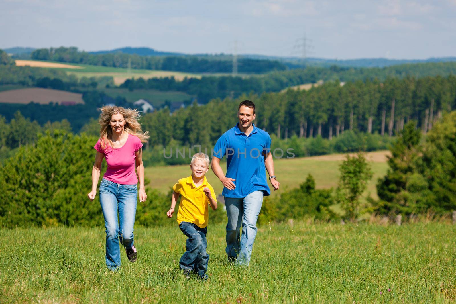 Family running on meadow in summer by Kzenon