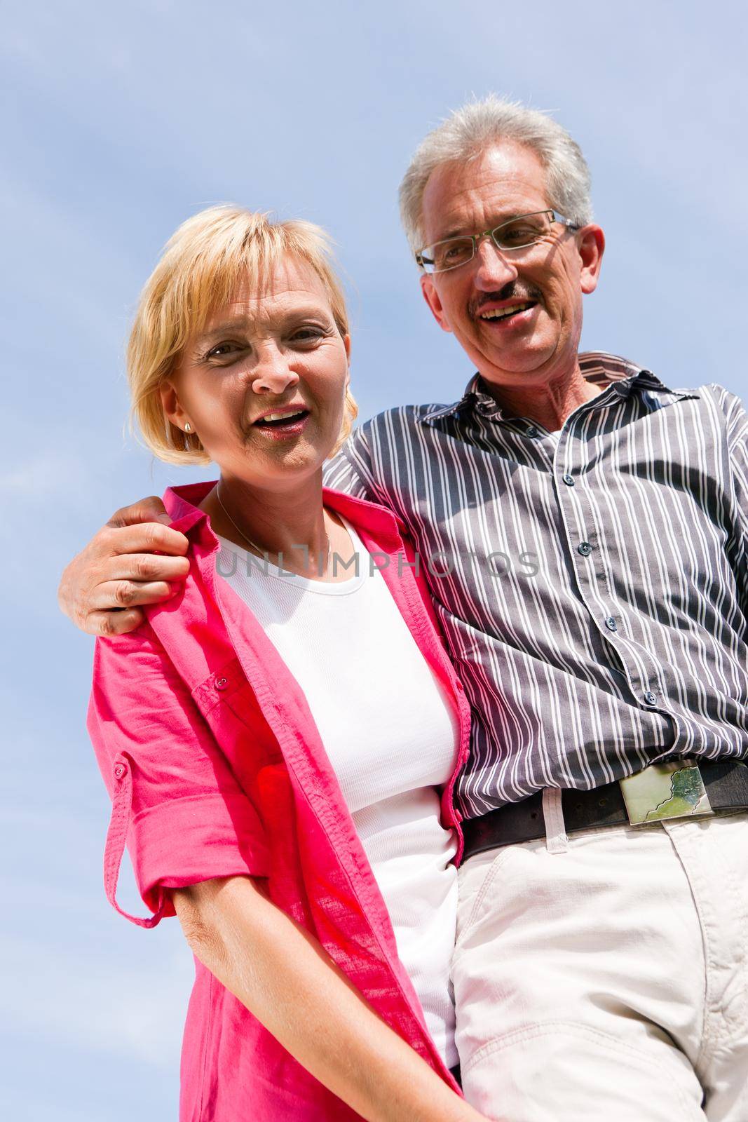 Visibly happy mature or senior couple outdoors arm in arm having a walk