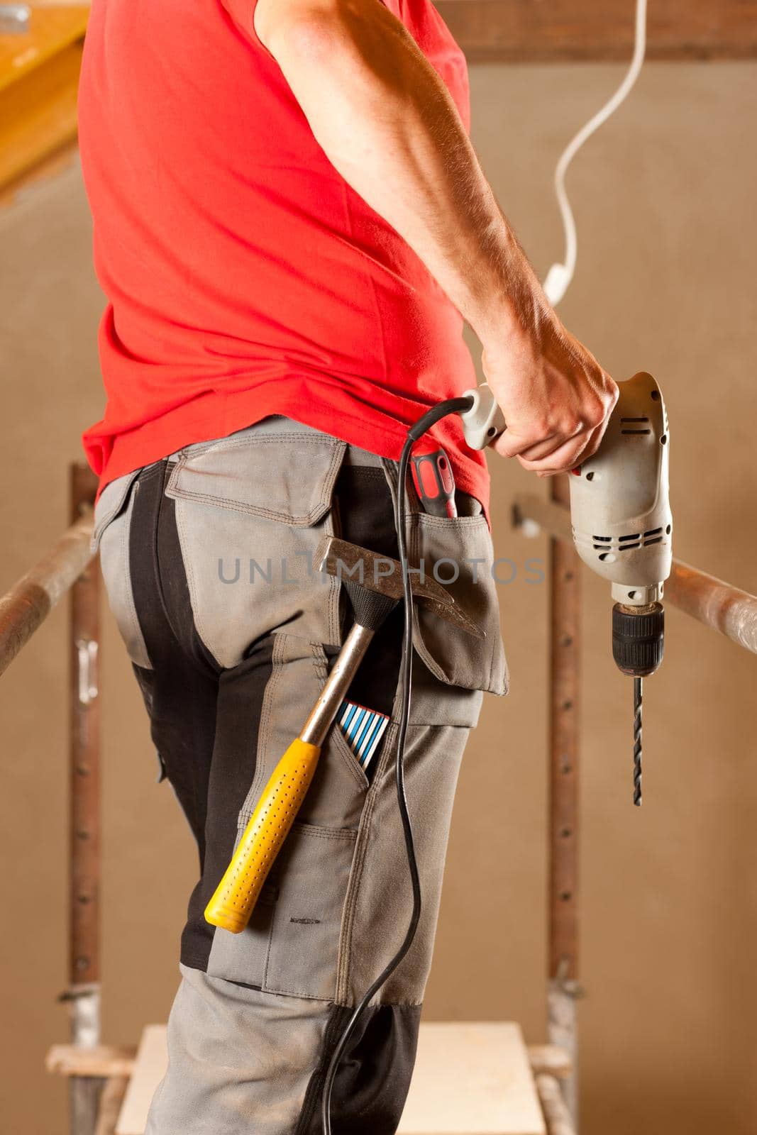 construction worker with hand drill standing on a scaffold