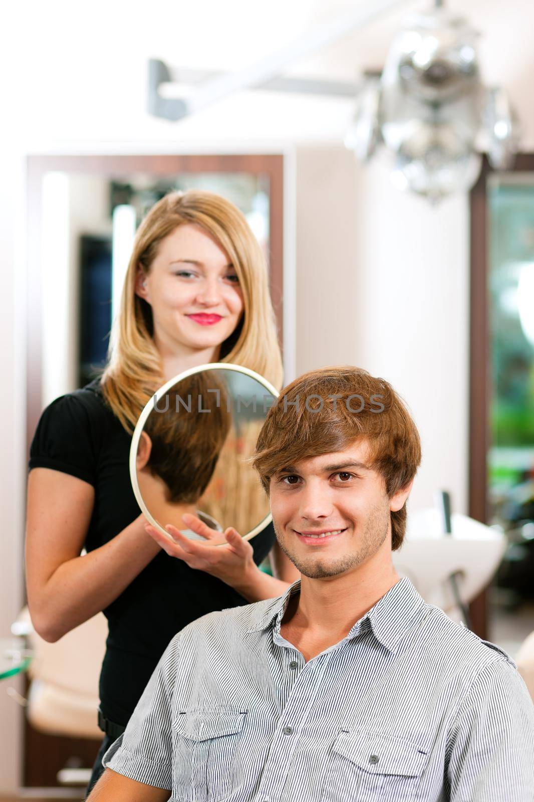 Man at the hairdresser, she has finished the cut and is showing the result in the mirror