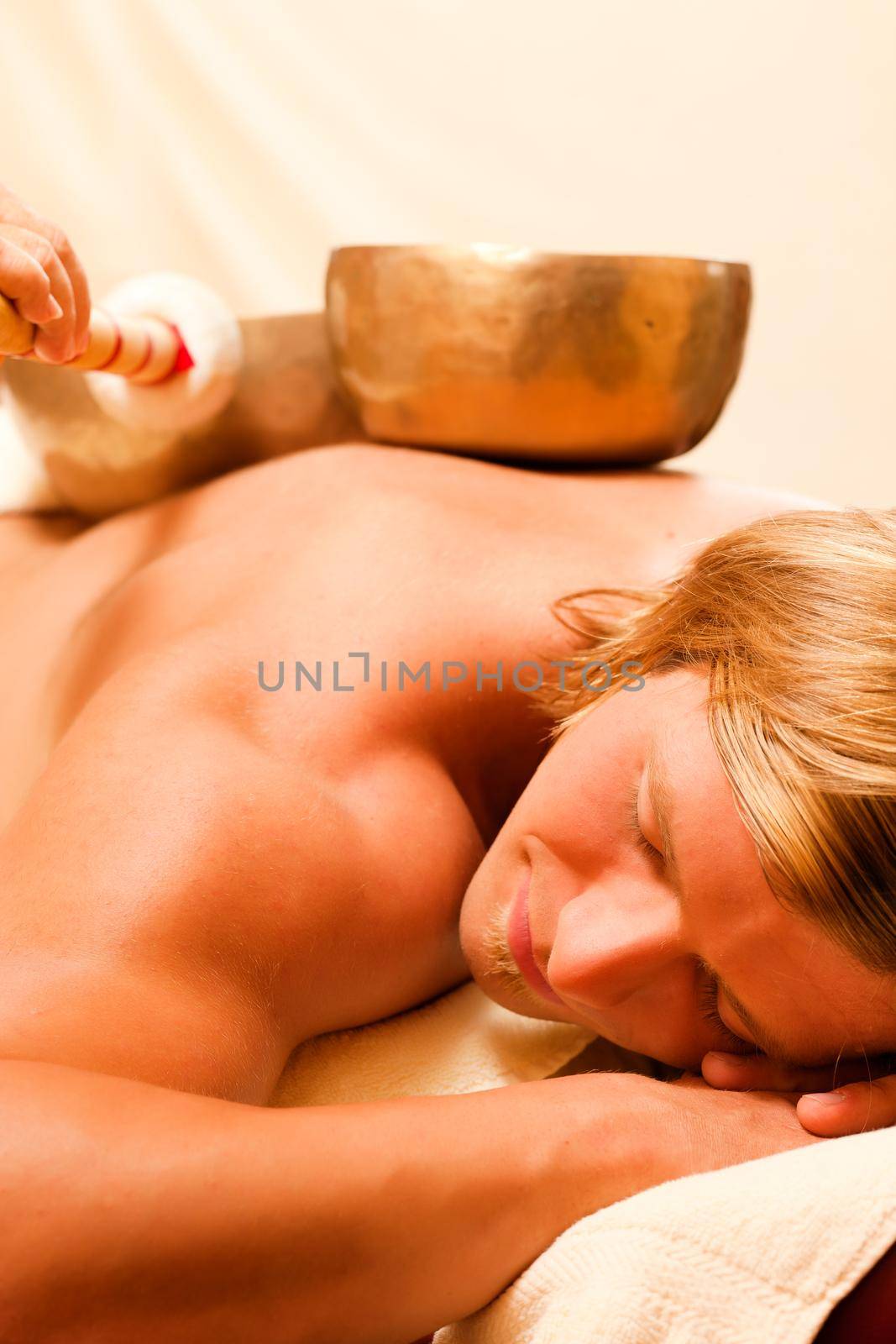 Man in wellness and spa setting having a singing bowl therapy session