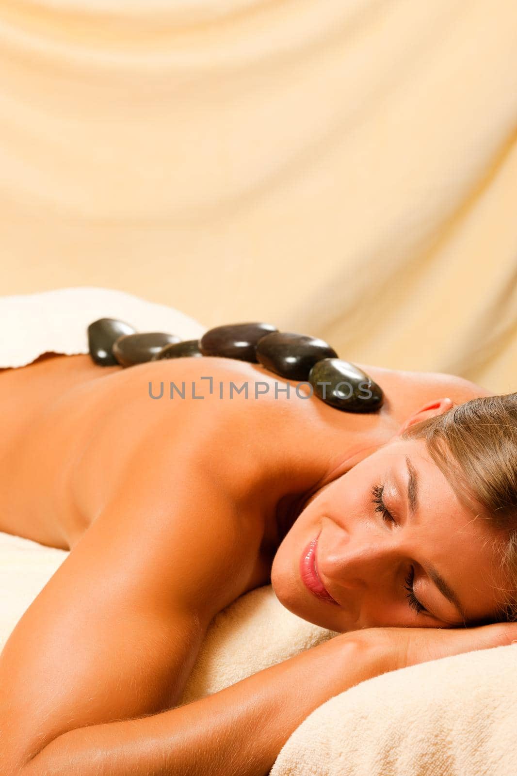 Woman in wellness and spa setting having a hot stone therapy session