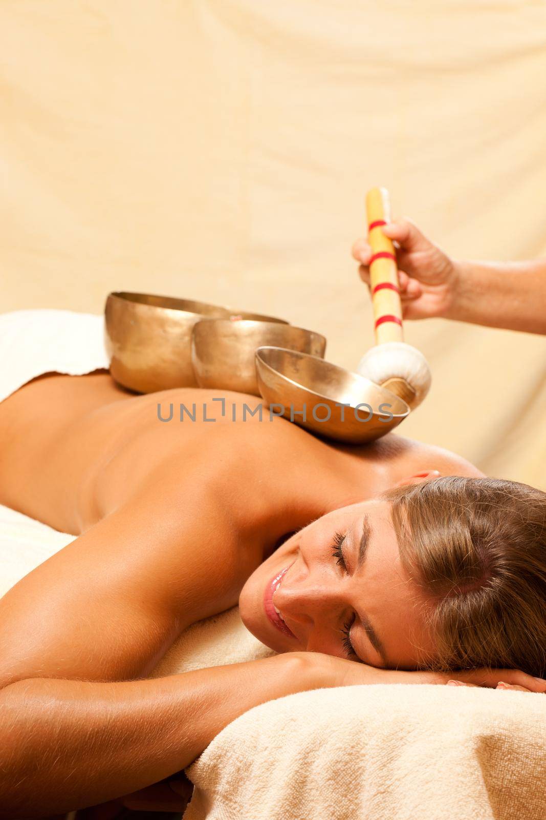 Woman in wellness and spa setting having a singing bowl therapy session