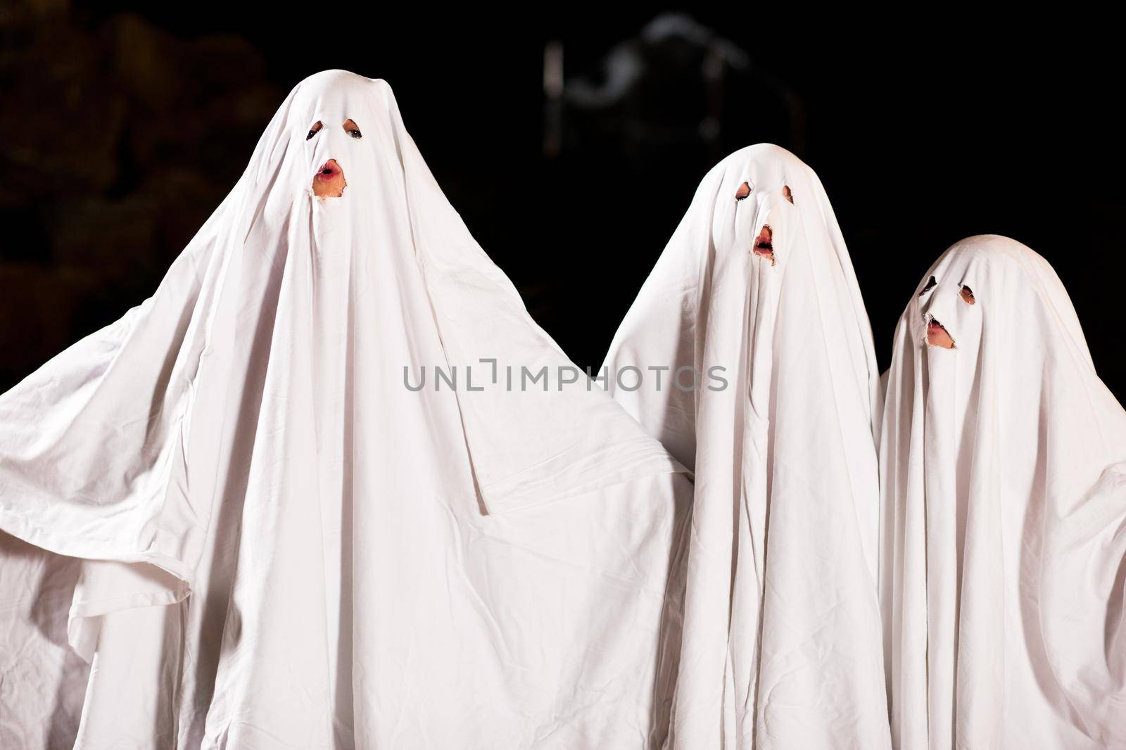 Three very, very scary spooks - kids dressed as ghosts - on Halloween or for carnival or a costume party