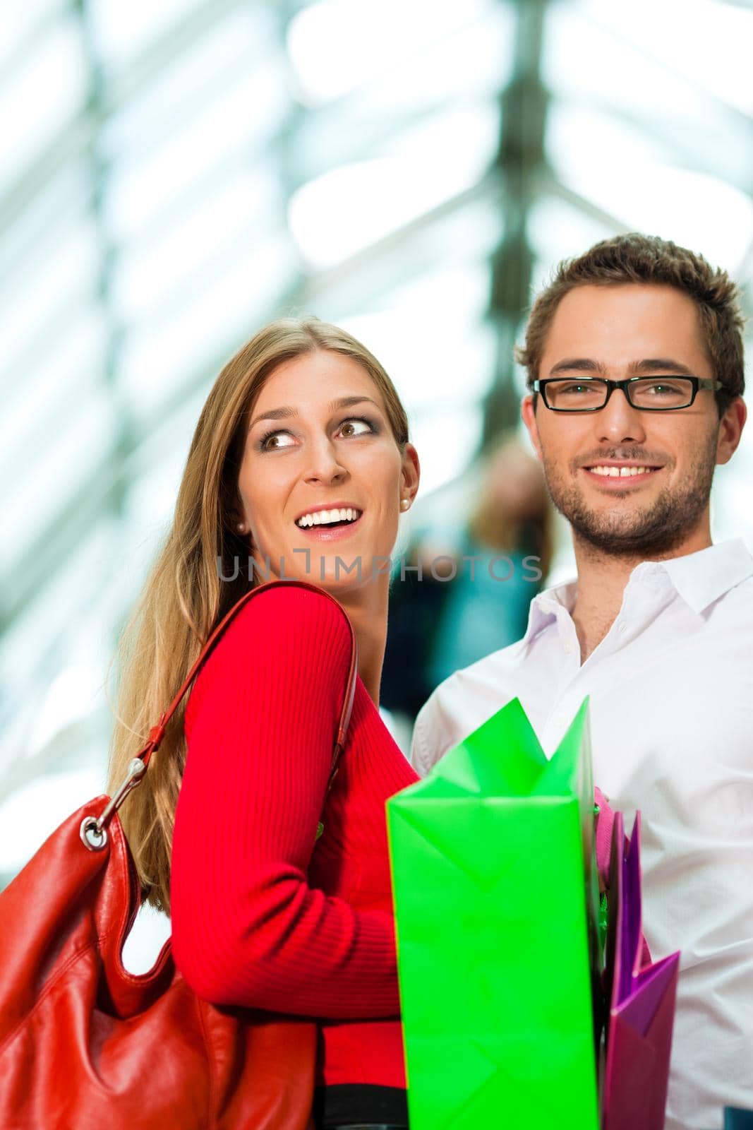 Couple - man and woman - in a shopping mall with colorful bags on an escalator