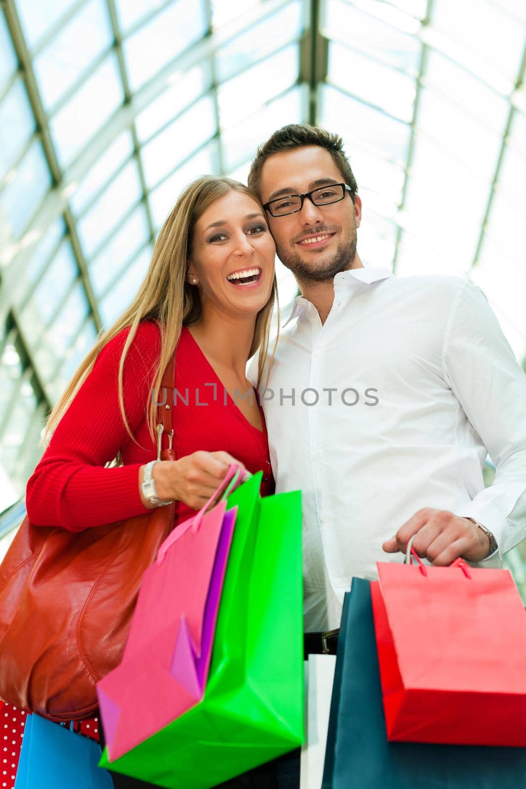 Couple - man and woman - in a shopping mall with colorful bags on an escalator