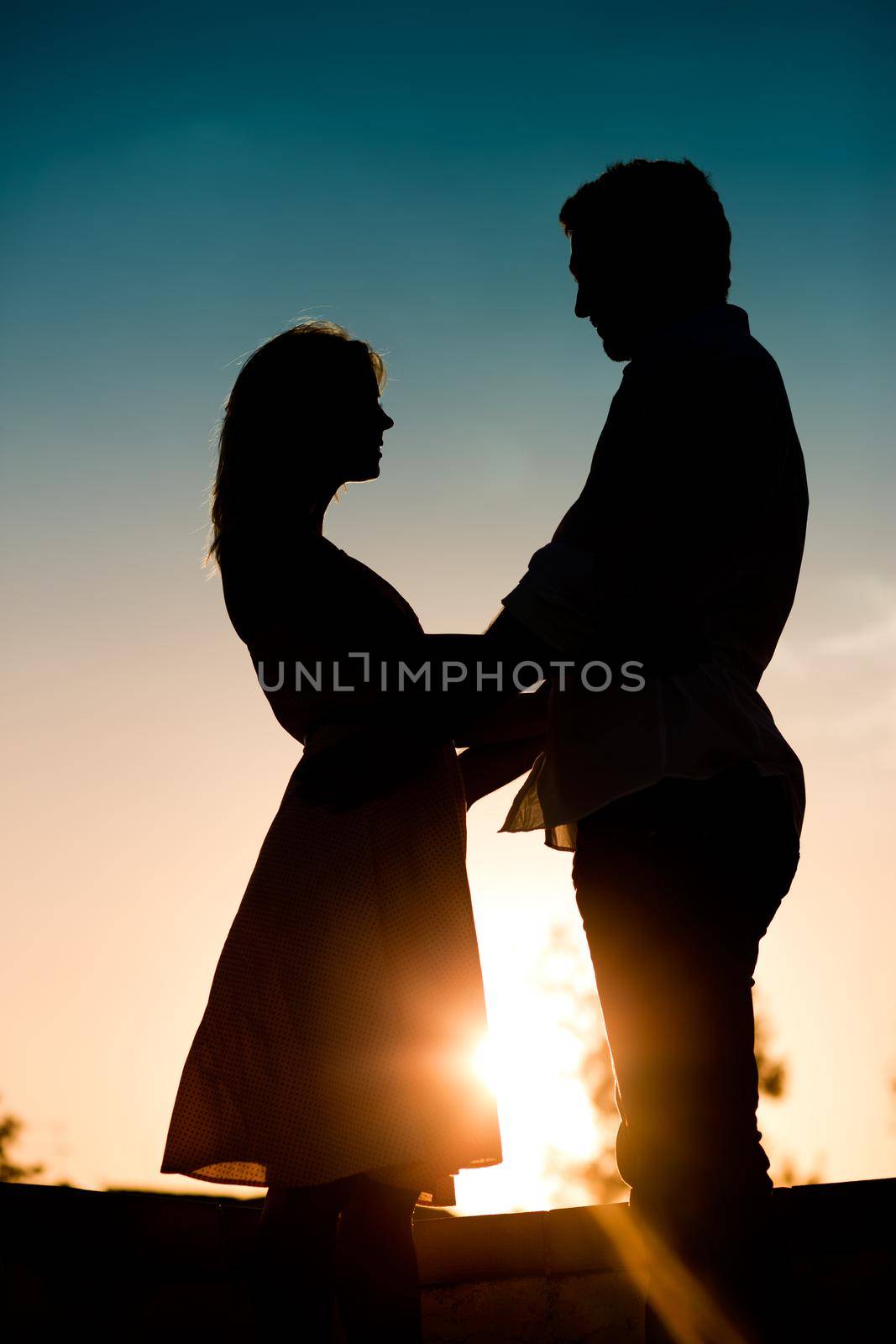 Couple in love touching each other backlit in a sunset in summer