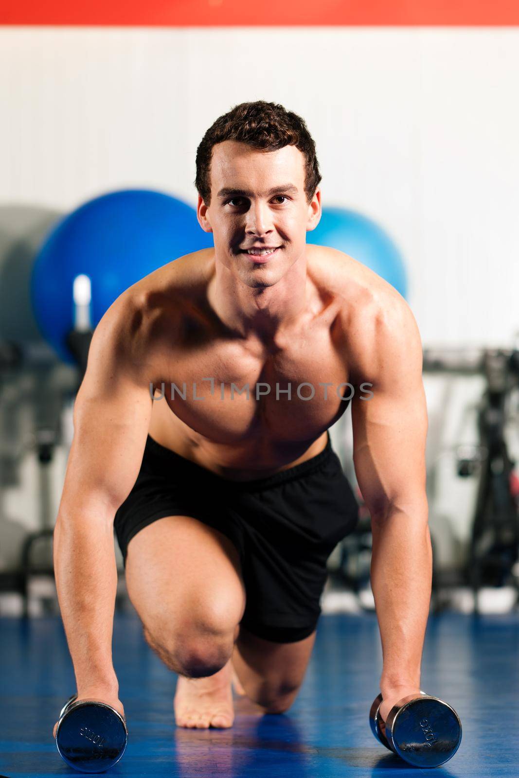 Very strong and muscular man exercising by starting pushups in a gym