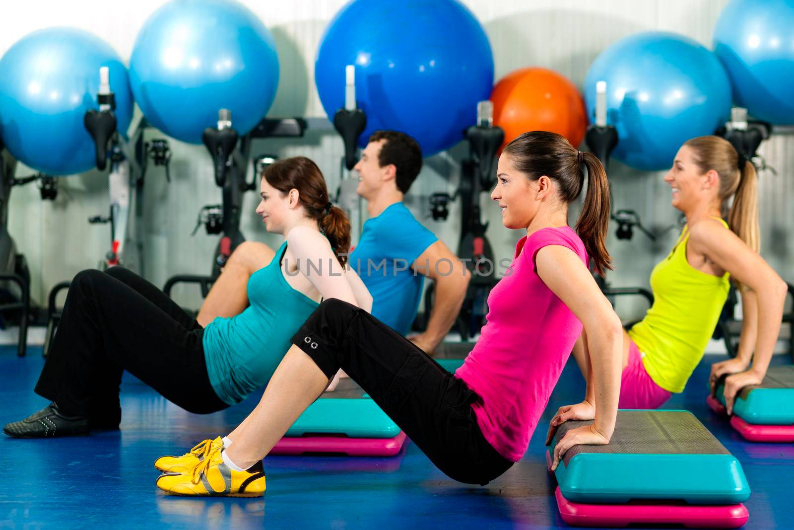 Fitness People in gym on step board; strengthening the abdominal muscles