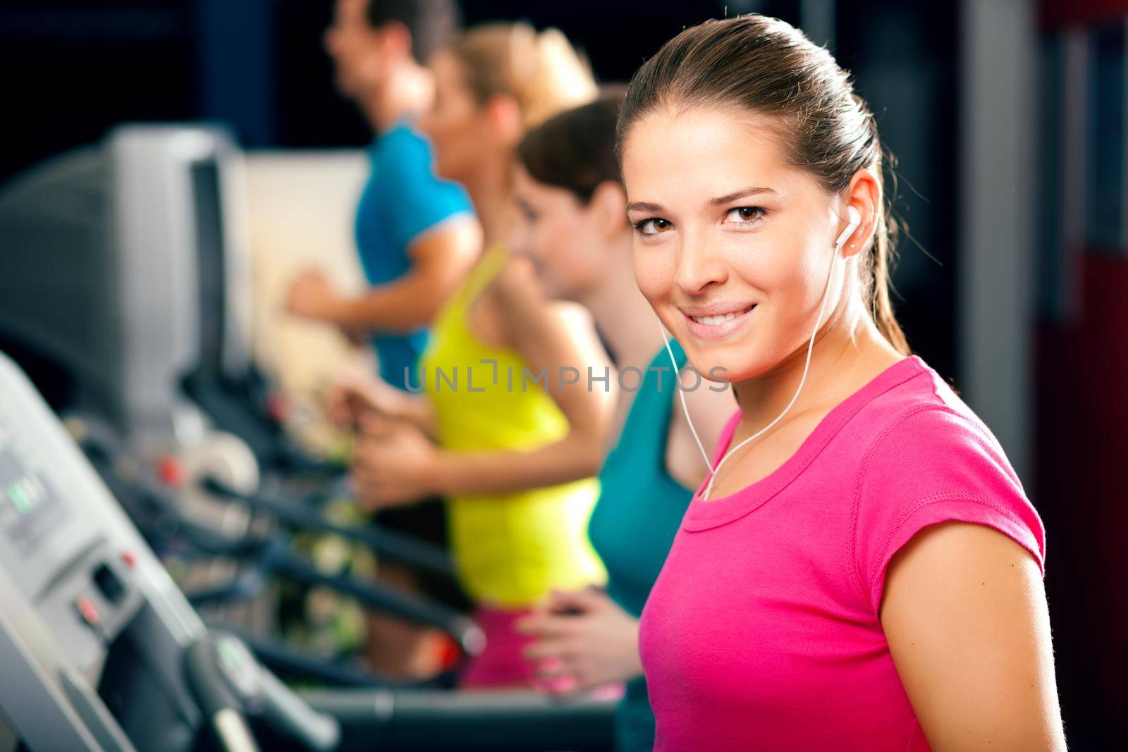 Running on treadmill in gym - group of women and men exercising to gain more fitness