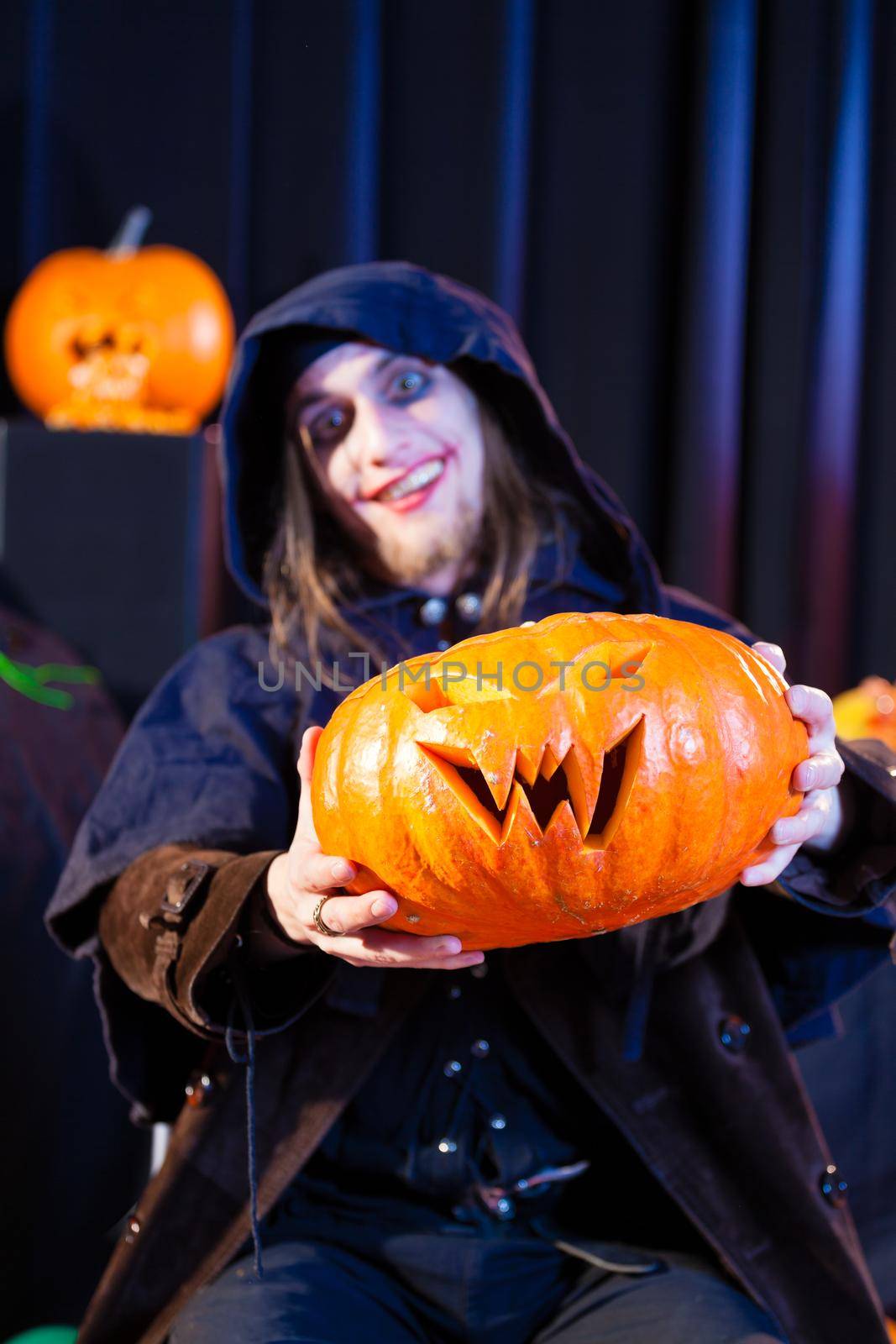 Man in scary Halloween costume holding pumpkin by Kzenon
