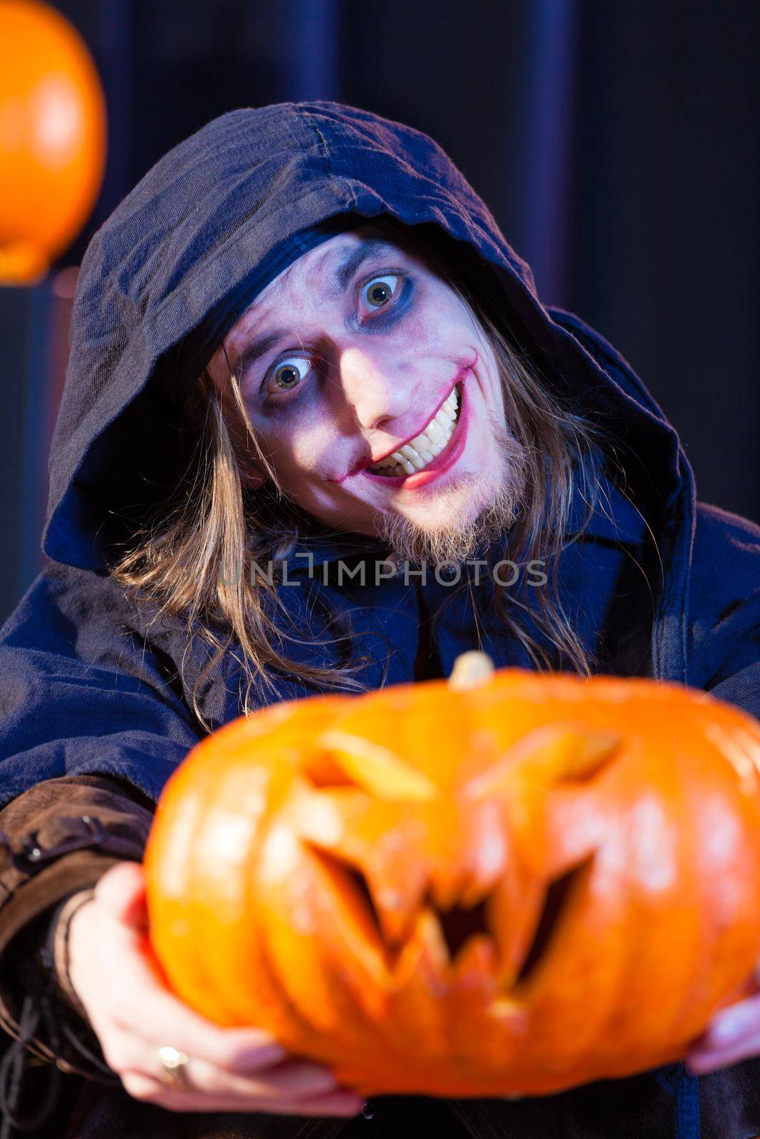 Man in scary Halloween costume holding pumpkin by Kzenon