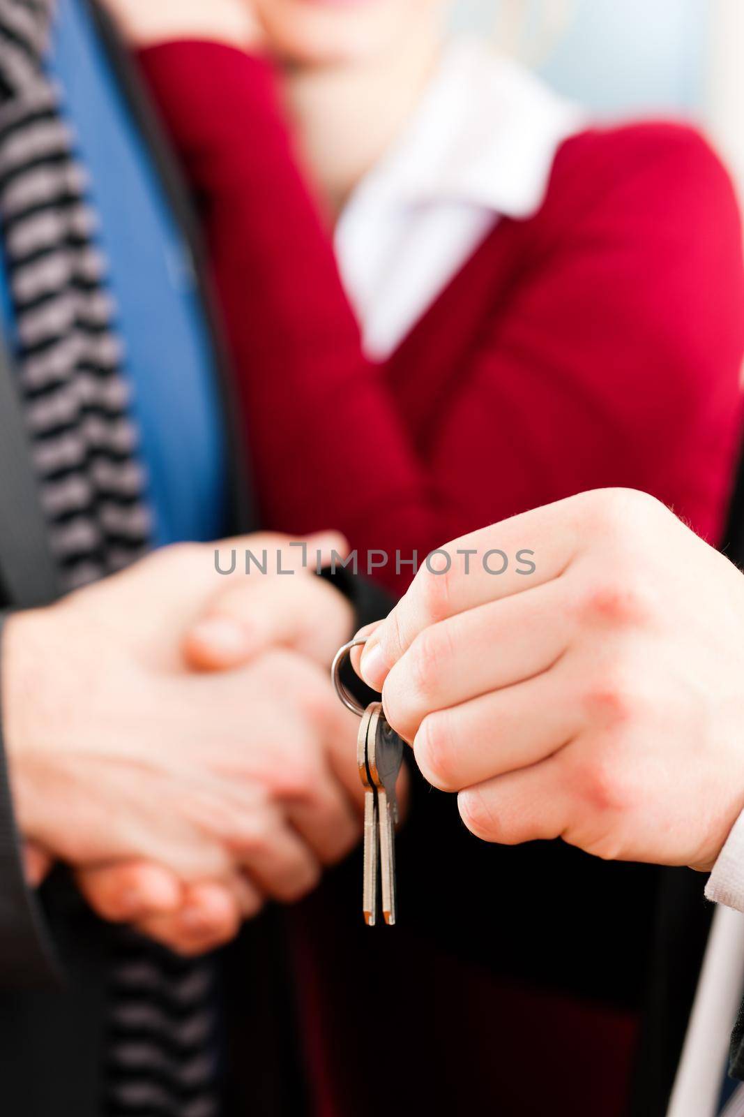 Couple receiving keys from real estate broker by Kzenon