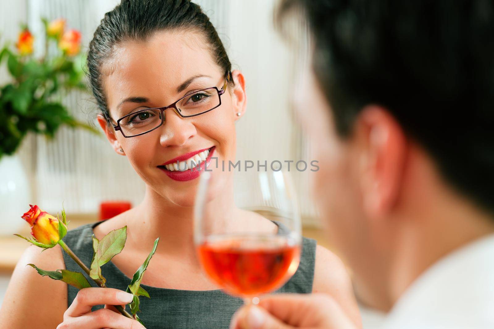 Young couple having romantic dinner - he is drinking rose wine