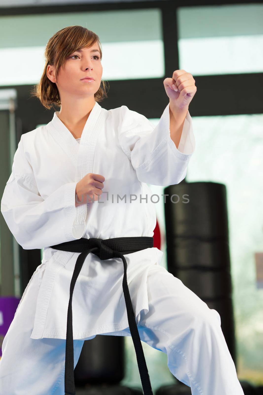 Woman in martial art training in a gym, she is wearing a black belt